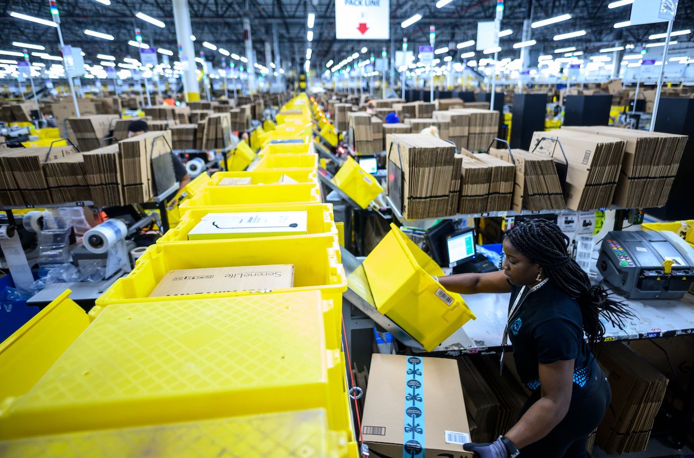 A woman works at a packing station at the 855,000-square-foot Amazon fulfillment center in Staten Island, one of the five boroughs of New York City, on February 5, 2019. - Inside a huge warehouse on Staten Island thousands of robots are busy distributing thousands of items sold by the giant of online sales, Amazon. (Photo by Johannes EISELE / AFP) (Photo credit should read JOHANNES EISELE/AFP via Getty Images)