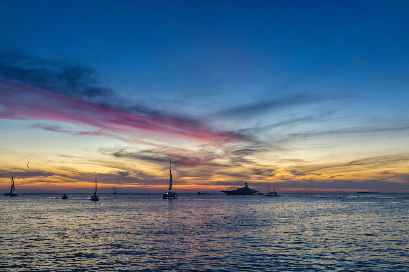 Silhouettes of boats and yachts at colorful sunset twilight blue hour with landscape view on blue cloudy sky with clouds by Mallory Square of Key West, Florida
