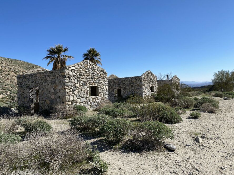 Three stone houses set in desert landscape