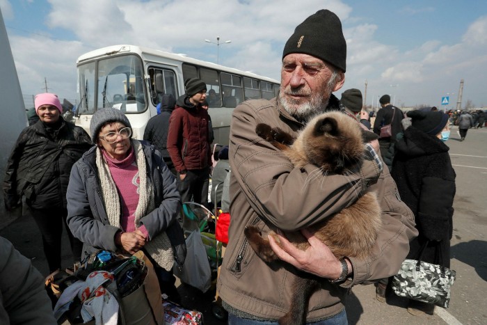 An evacuee holds a cat while waiting to board a bus leaving Mariupol
