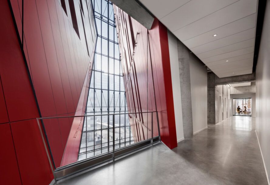A glass window with red designs on both sides, like curtains, fills a wall in the hallway