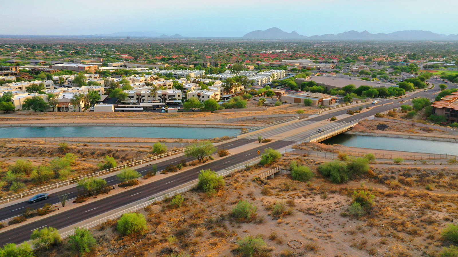 Scottsdale, Arizona highway across a river with buildings, greenery and mountains in the distance